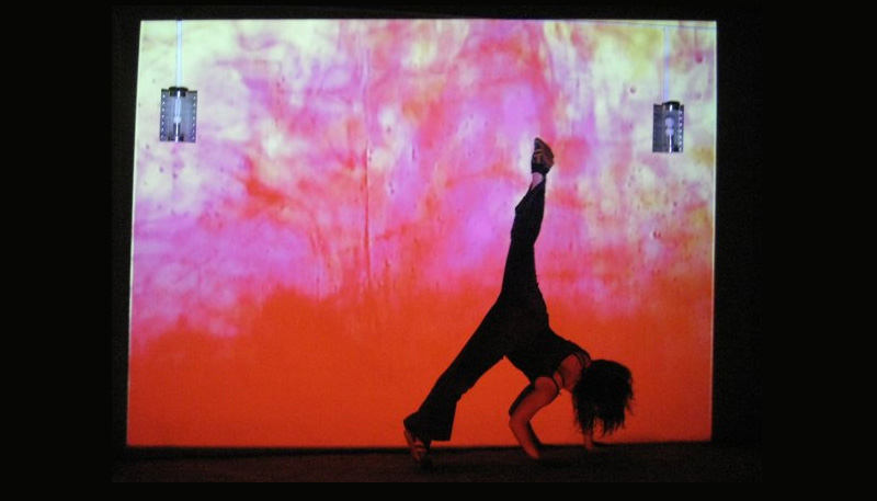screenshot of video with dancer in front the fluid projection